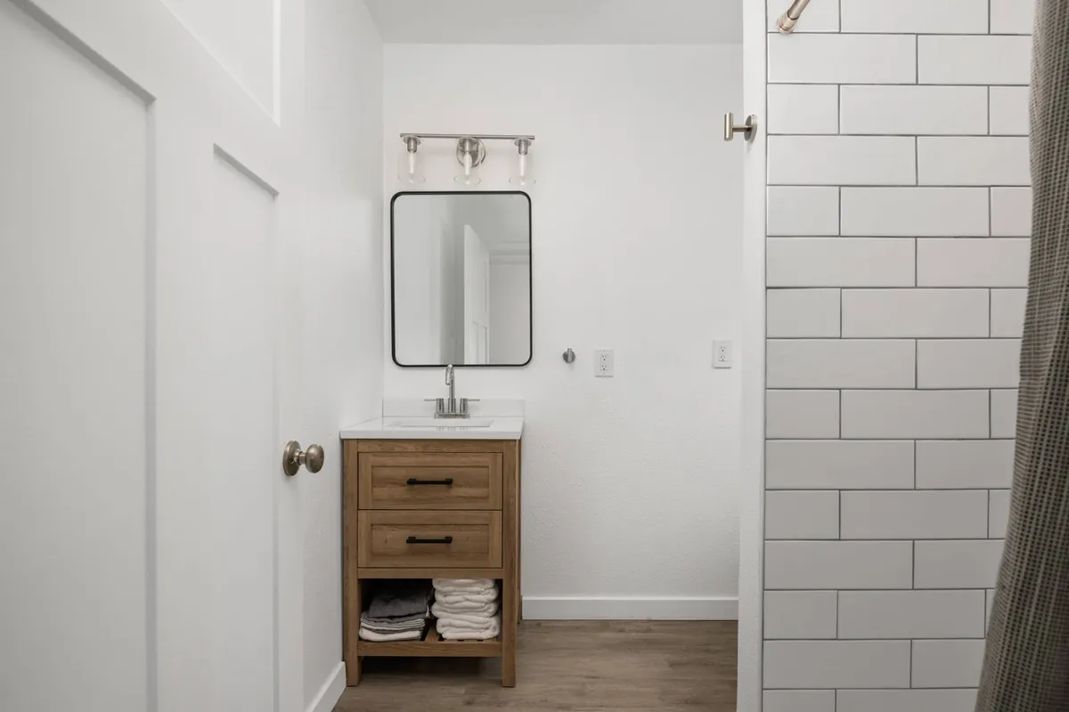 A refreshing, inviting bathroom scene with a modern vanity, sink, mirror, and fresh towels. The design is clean and spa-like, ideal for after-beach refreshment. The image evokes comfort and convenience, aligning perfectly with the section’s description of the adjacent full bath.