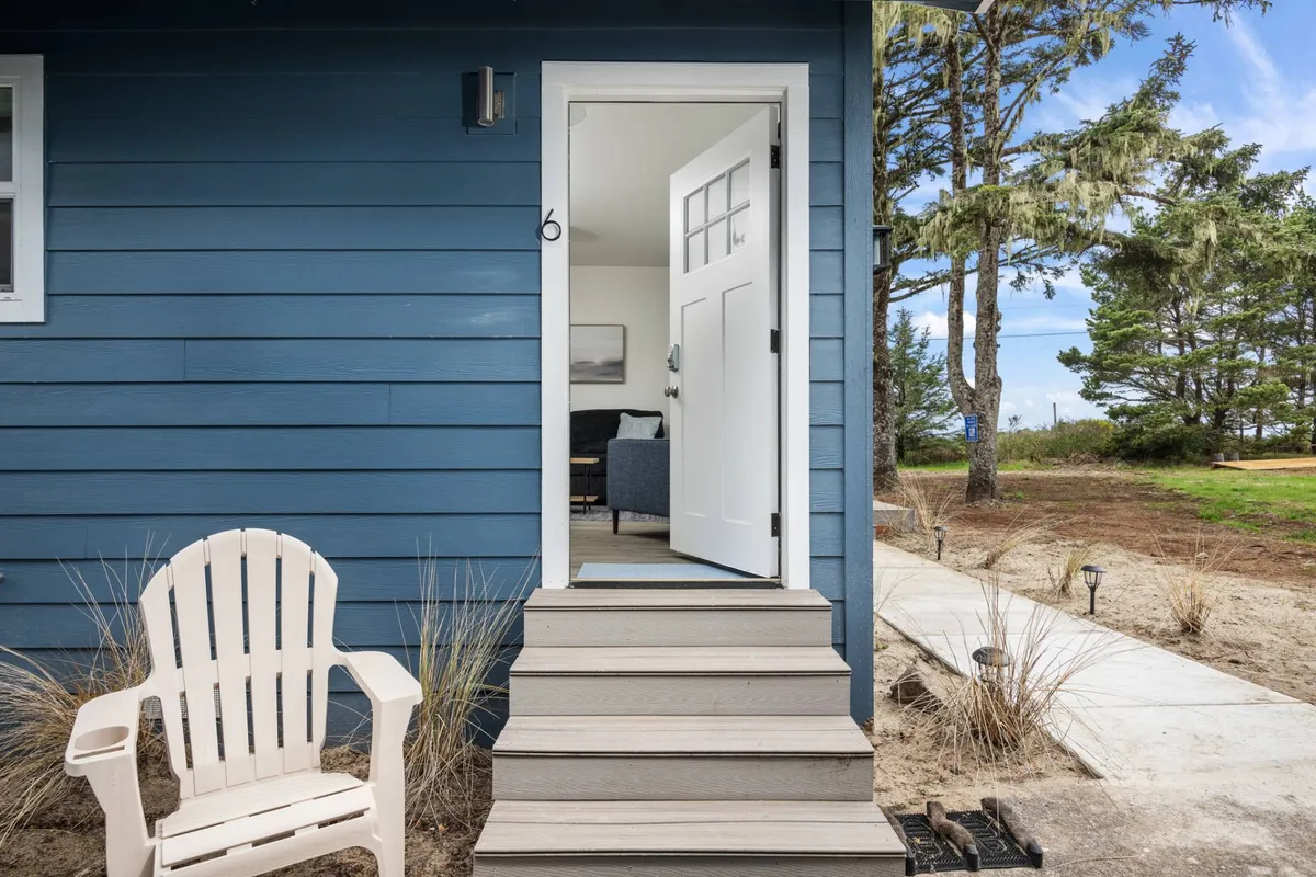 A charming shot of the unit’s front door with a white Adirondack chair on a landscaped path. The inviting porch area suggests a spot for relaxing, sharing stories, or keeping an eye on the kids at play.