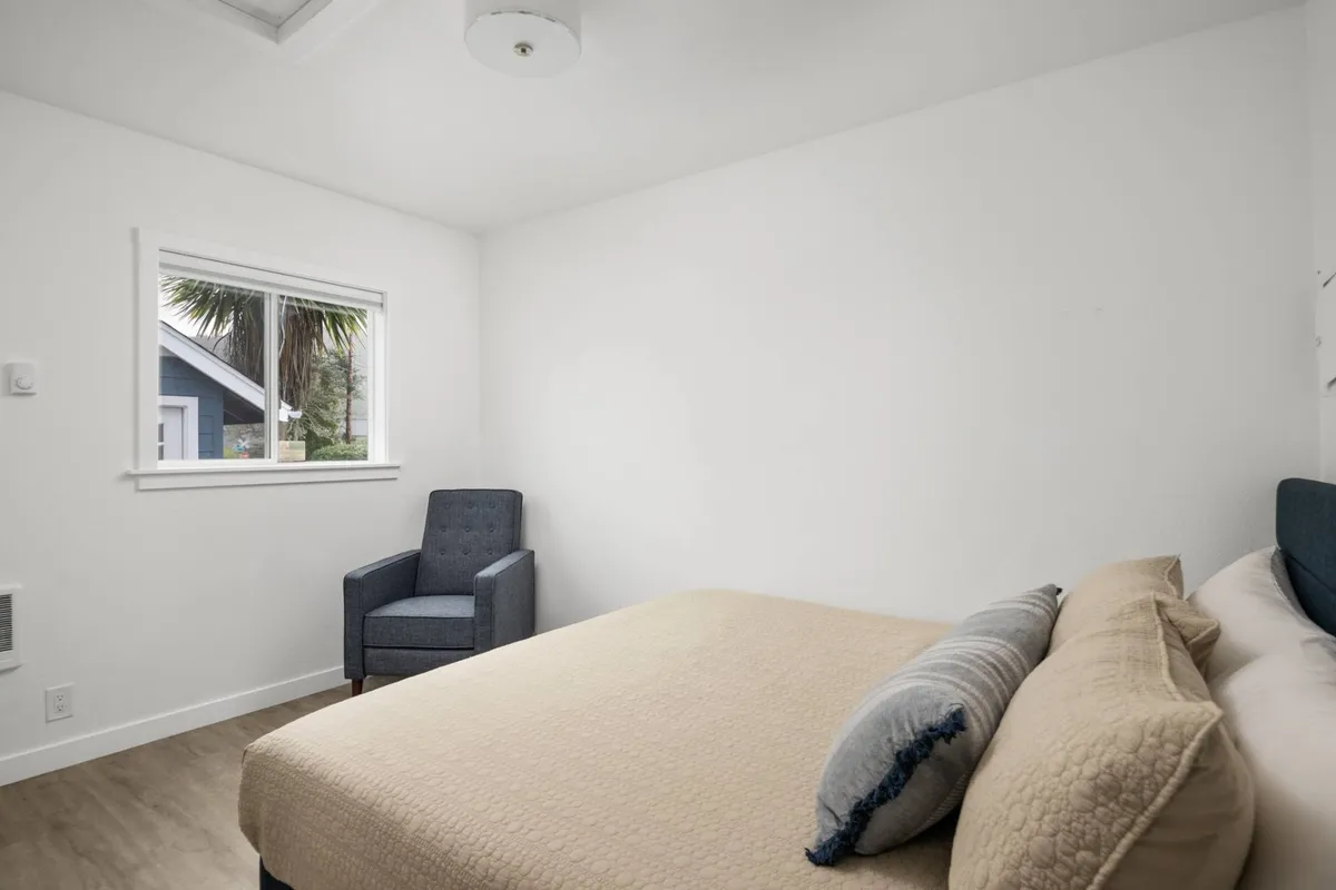 A serene interior space with a comfortable bed, cozy chair, and a sunlit window. The room radiates comfort and relaxation, offering a warm home base for all guests after outdoor adventures.